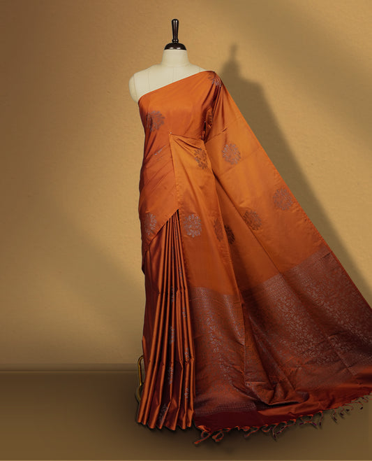 Brown colour semi soft silk saree featuring intricate woven floral motifs on the body, complemented by a rich woven border and pallu with tassel finish & Comes with a matching blouse piece for an elegant look.