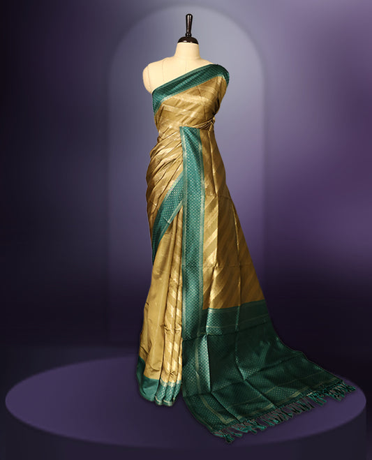 Golden saree featuring subtle self striped woven patterns on the body, enhanced with a green geometric border, complemented by a rich zari pallu with tassels, and paired with a matching blouse for a traditional elegant look.