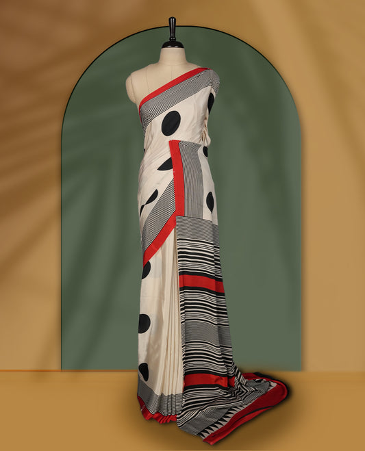 Cream colour saree with bold black polka dots, striped detailing, and striking red border & Comes with a stylish matching blouse.