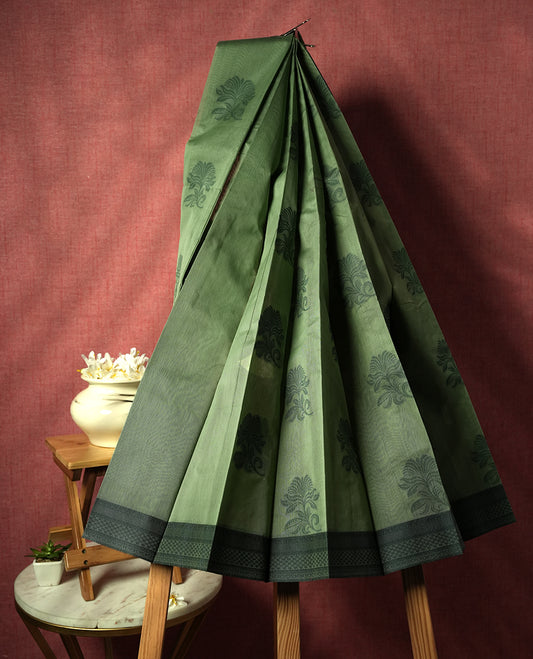 Pastel green colour silk cotton saree featuring elegant floral zari motifs on the body, complemented by a rich contrast dark green border and pallu with traditional woven detailing & Comes with a matching blouse piece.