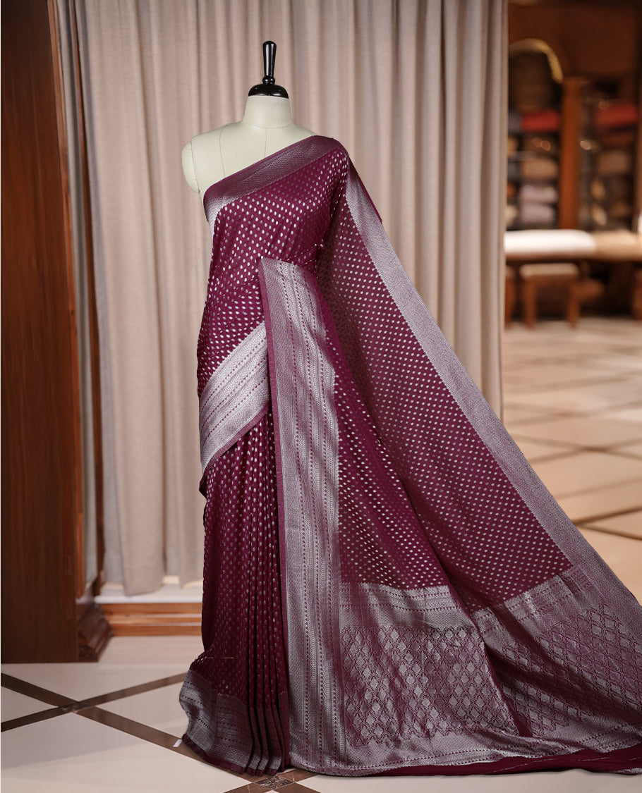 Wine colour Banarasi silk saree featuring intricate zari weaving and a soft silk texture, Adorned with silver motifs on the body, complemented by a rich Banarasi border and pallu & Comes with a matching blouse.
