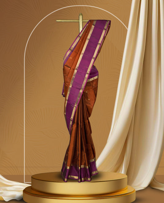 Brown colour soft silk saree adorned with golden zari motifs, complemented by a rich purple border and pallu & Paired with a matching blouse.