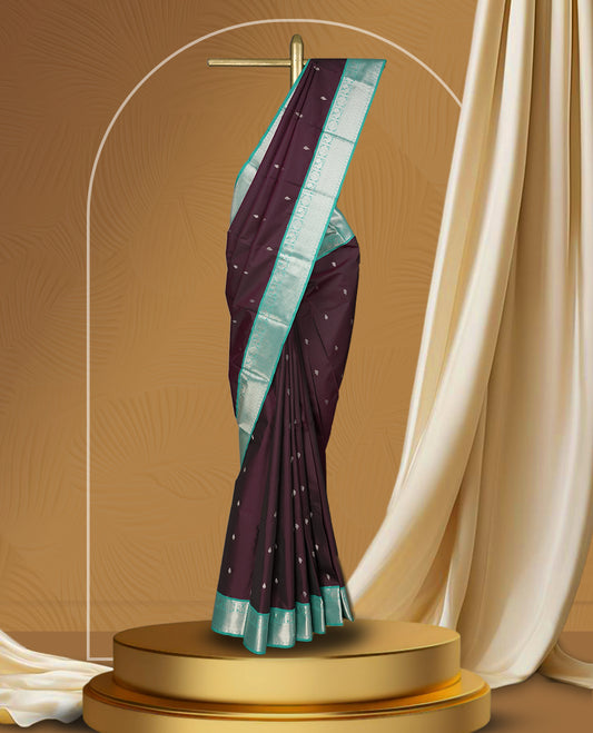 Deep plum colour body soft silk saree adorned with silver buttas, paired with a contrasting light aqua green zari border & Comes with a matching blouse.