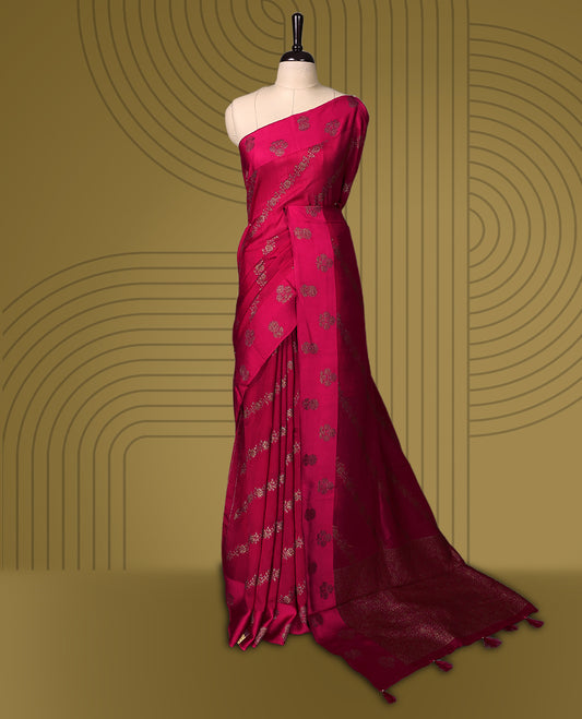 Rani pink semi Banaras tussar saree adorned with golden floral motifs in diagonal patterns across the body and a beautifully woven zari border, finished with a rich golden pallu, paired with a matching blouse.