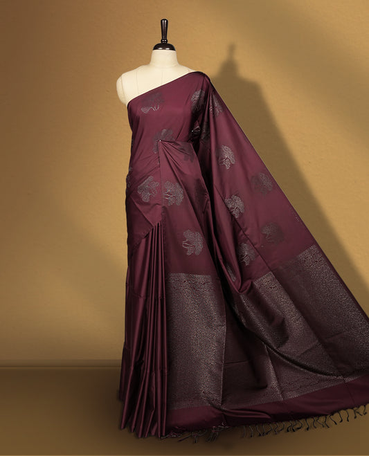 Deep brown colour semi soft silk saree, adorned with subtle floral woven motifs on the body & The design is elevated with an elegant zari border and pallu, paired with a matching blouse.