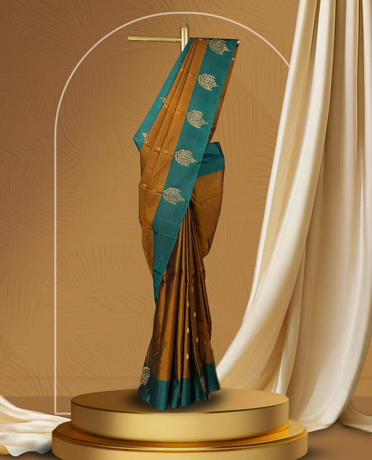 Coffee brown colour soft silk saree adorned with intricate golden zari motifs, teal green colour border for a perfect blend of tradition & Paired with a matching blouse.
