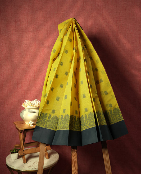 Chrome yellow colour silk cotton saree featuring elegant floral zari motifs on the body, complemented by a rich contrast dark plain grey border and pallu with traditional woven detailing & Comes with a matching blouse piece.