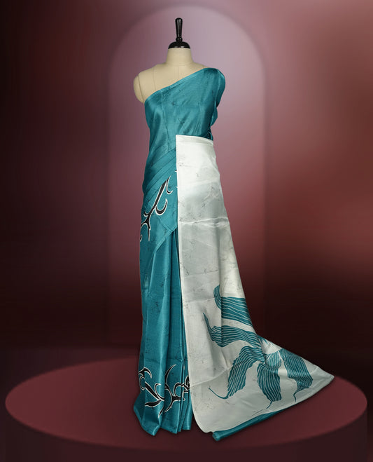 Teal blue colour saree adorned with bold off white floral prints, blending tradition with a modern twist & paired with a matching blouse.