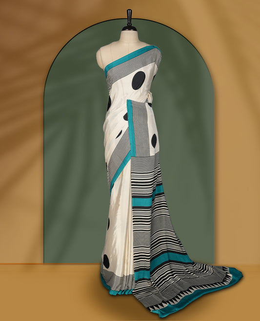Ivory white colour saree with bold black polka dots and fine stripe detailing, elevated by a vibrant teal border & The striking pallu design adds charm. Lightweight and elegant, paired with matching blouse.