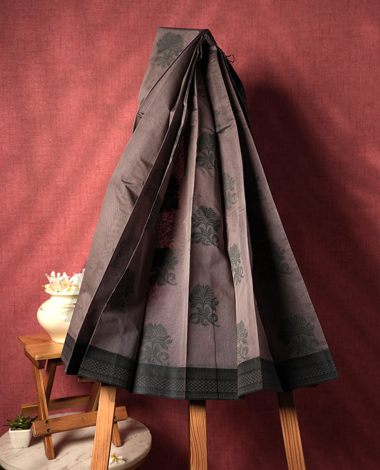 Dusty grey colour silk cotton saree featuring elegant floral zari motifs on the body, complemented by a rich contrast dark greenish border and pallu with traditional woven detailing & Comes with a matching blouse piece.