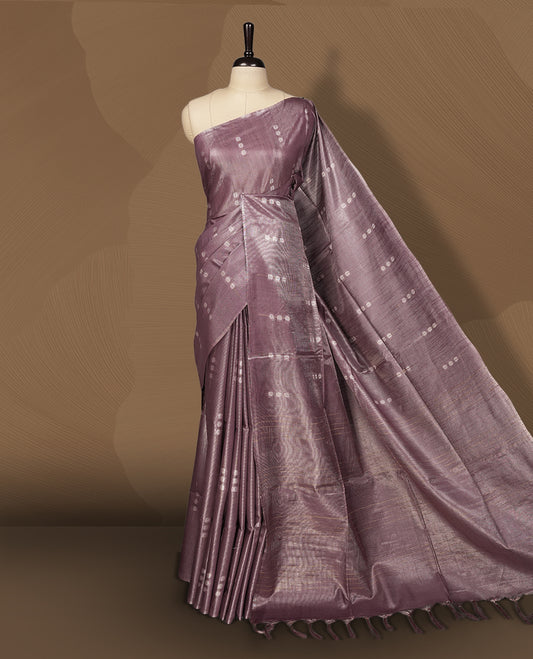 Mauve semi jute tissue saree featuring subtle dotted woven patterns on the body, complemented by a shimmering pallu and sleek zari border & Comes with a matching blouse piece for a complete look.