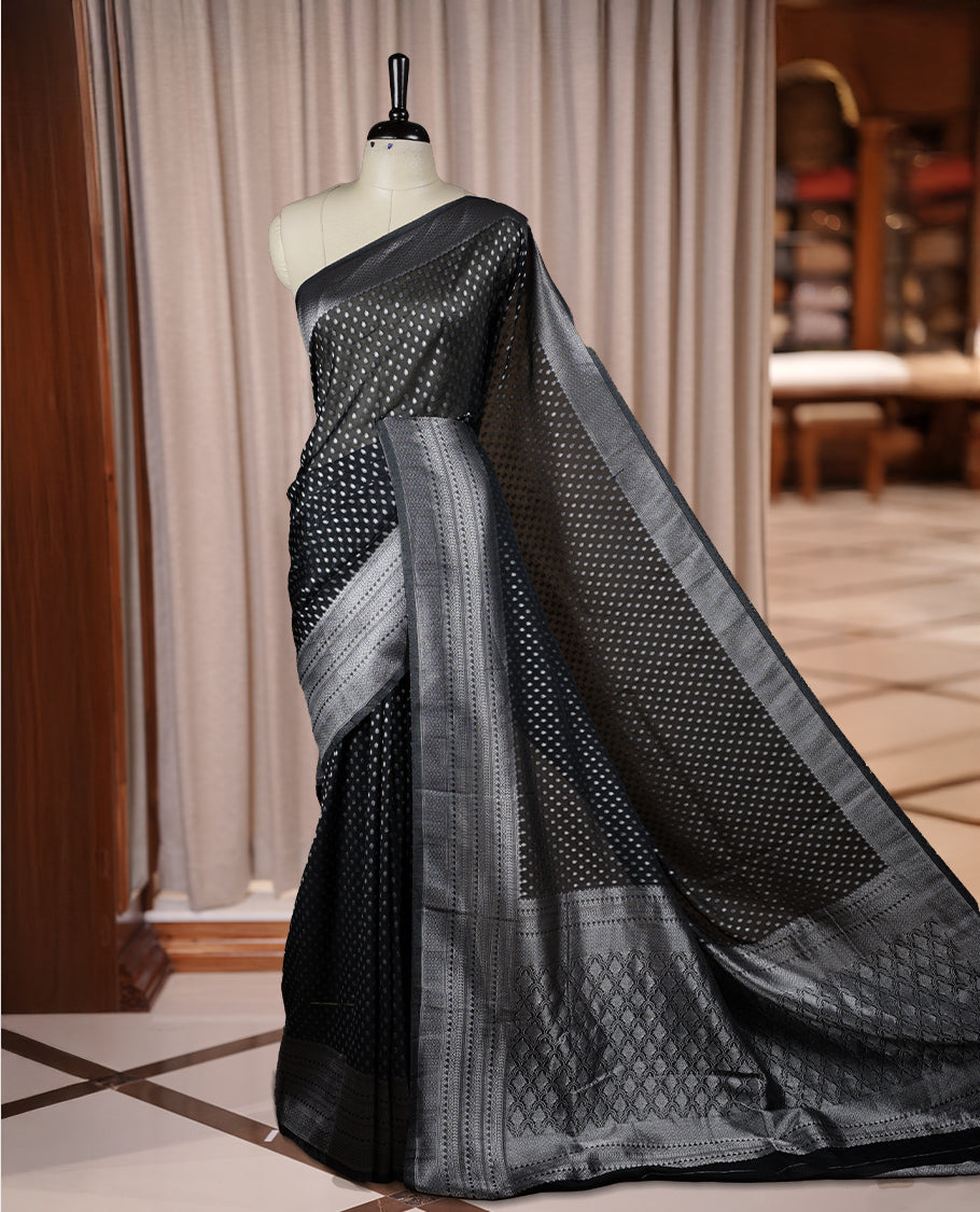 Black colour Banarasi silk saree featuring intricate zari weaving and a soft silk texture, Adorned with silver motifs on the body, complemented by a rich Banarasi border and pallu & Comes with a matching blouse.