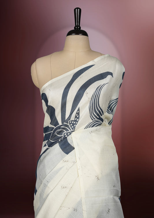 Grey and off white colour saree featuring bold floral and abstract prints across the body and pallu, offering a perfect blend of elegance and modern style, paired with a matching blouse piece.