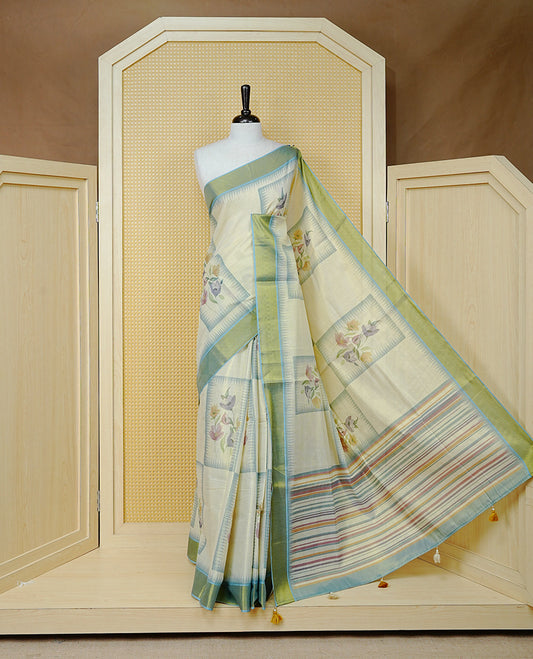 Cream Colour Tissue Kerala Saree Featuring Floral Prints in a Stylish Rectangle Pattern On Body, Enhanced with an Olive Green and Light Blue Zari Border, Multicoloured Striped Pallu Is Finished with Elegant Tassels and Paired with a Matching Blouse Piece.