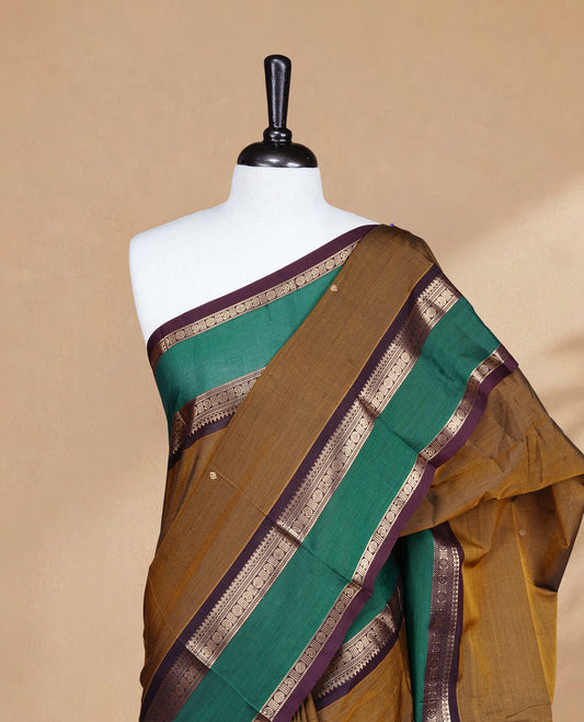 Olive colour Chettinad Silk cotton saree featuring Elegant body, complemented by Contrast Green & Chocolate colour with Gold zari border, paired with matching blouse piece.