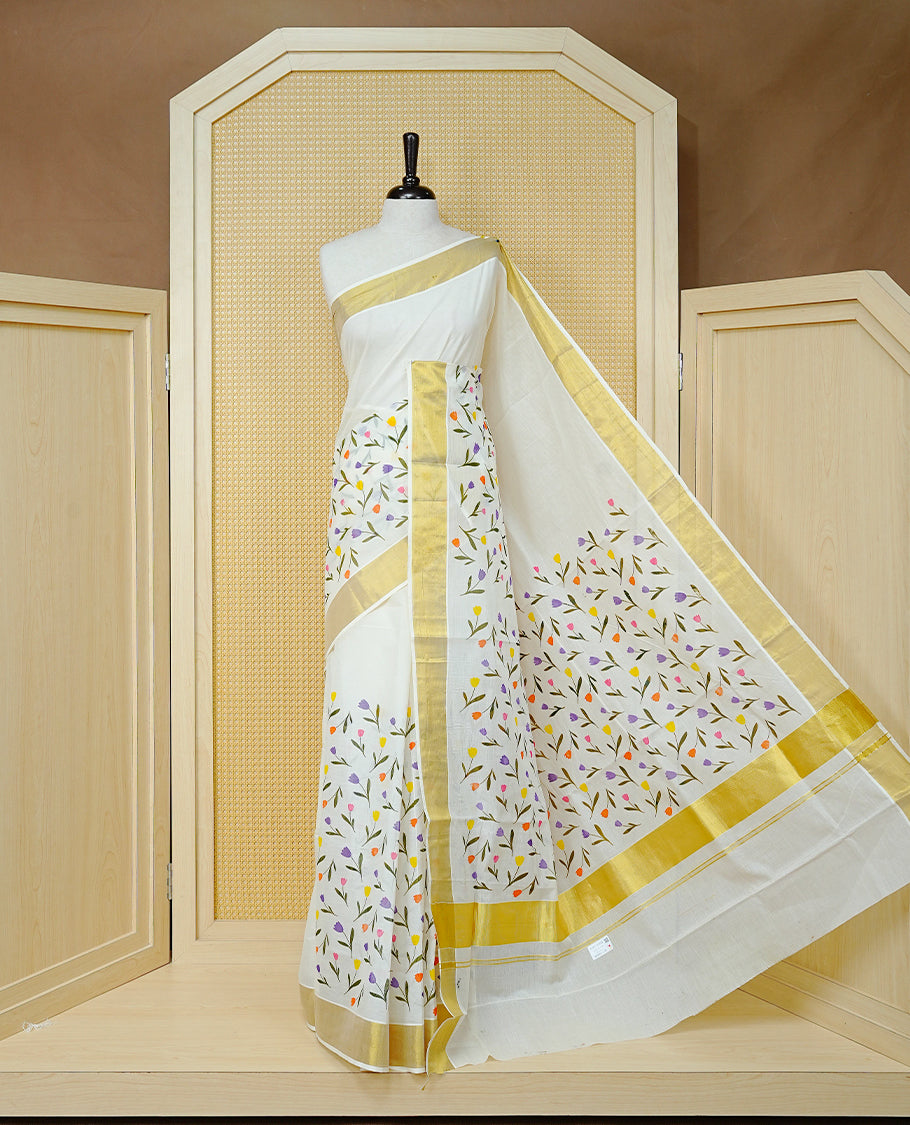 Cream Colour Cotton Kerala Saree Featuring Digital Floral  Motifs On Body, With A Classic Gold Zari Border & A Gold Zari Pallu, Paired With A Matching Blouse Piece.