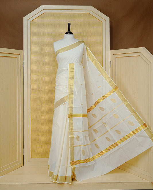 Cream Colour Cotton Kerala Saree Featuring Delicate Gold Zari Leaf Pattern  Across The Body, Enhanced With A Traditional Gold Zari Border , A Gold Leaf Motifs Striped Gold Zari Pallu, Finished With A Matching Blouse Piece