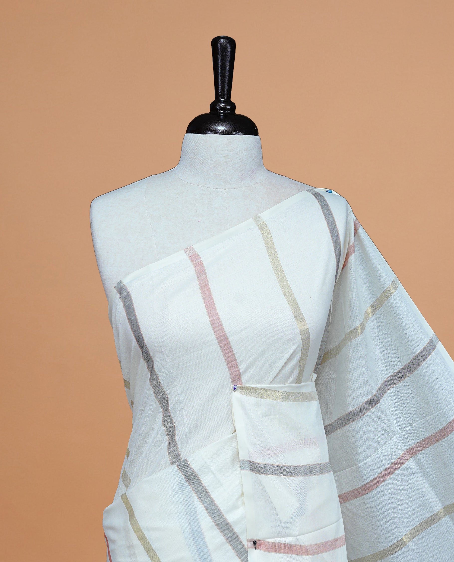 Cream Colour Cotton Kerala Saree Featuring Gray & Light Red Strips On The Body & Pallu, Paired With A Matching Blouse Piece.