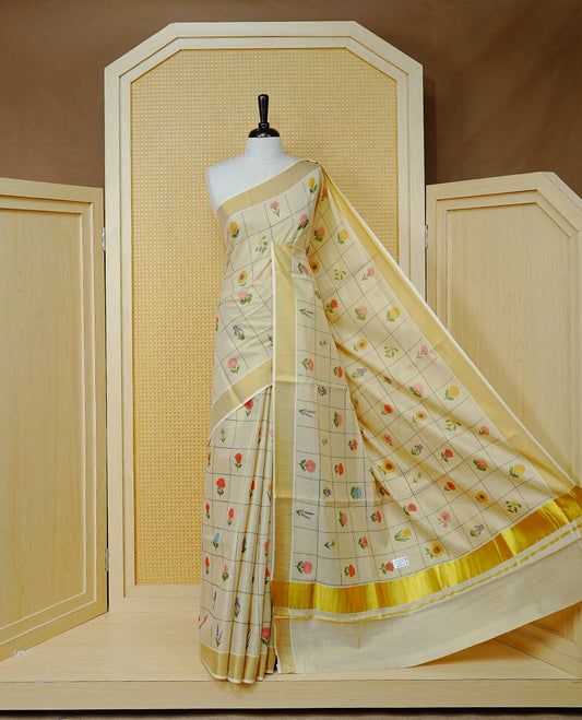 Cream Colour Tissue Kerala Saree Featuring Multicolour Floral Motifs In A Checked Pattern Across The Body, Enhanced With A Gold Zari Border And A Traditional Gold Zari Pallu, Finished With A Matching Blouse Piece