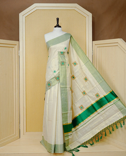 Cream Colour Tissue Kerala Saree Featuring Delicate Green  Floral Embroidery Work Across The Body, Enhanced With A Light Green  Zari Border And A Rich Green & Gold Zari Pallu, Finished With Green Tassels And A Matching Blouse Piece