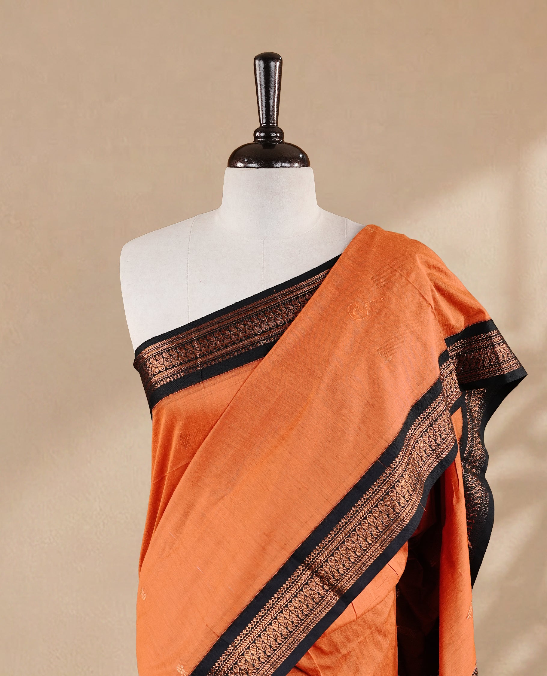 Orange colour kalyani cotton saree featuring antique zari motifs on body, complemented by Black colour with Antique zari border, paired with matching blouse piece.