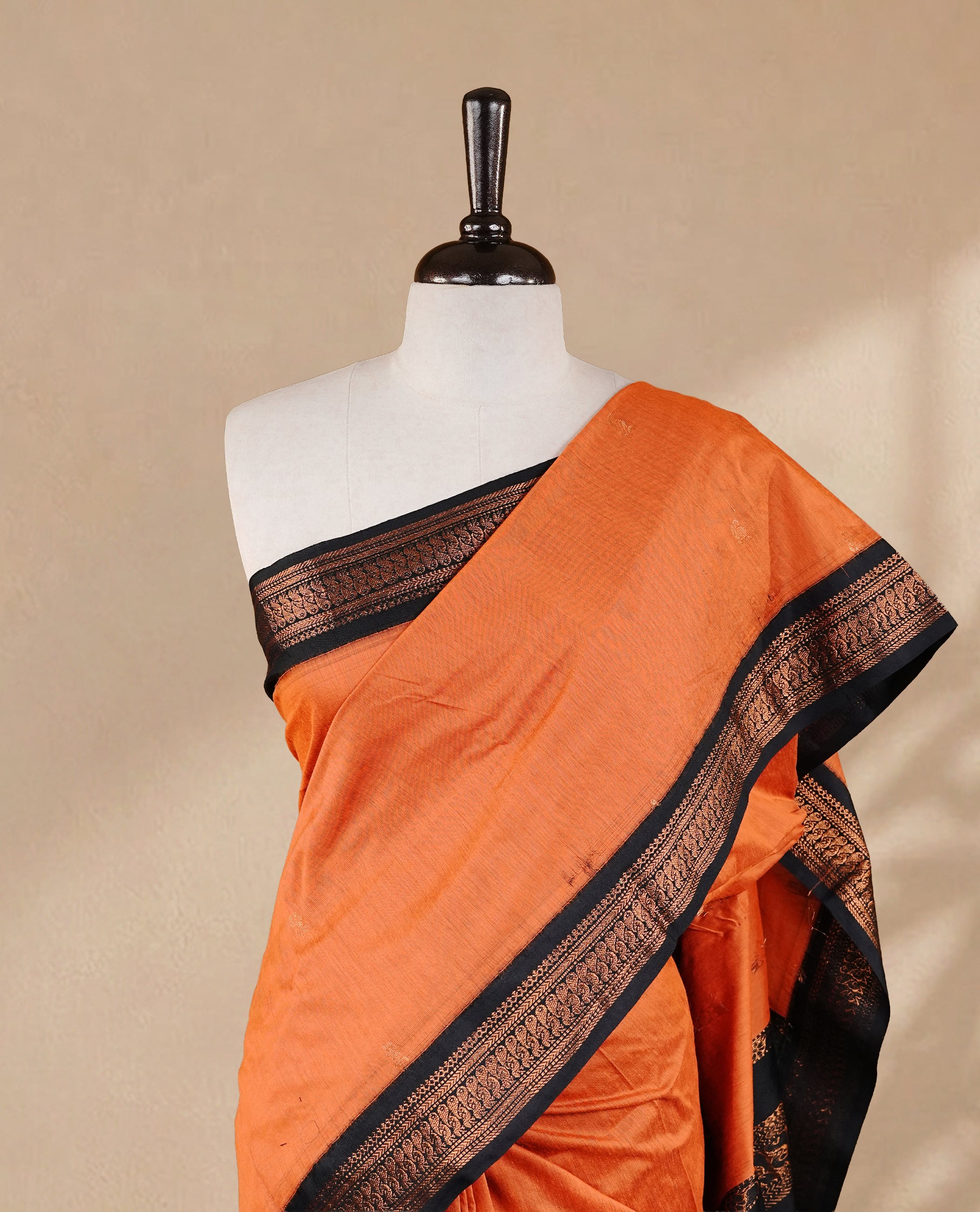 Orange colour kalyani cotton saree featuring antique zari motifs on body, complemented by Black colour with Antique zari border, paired with matching blouse piece.