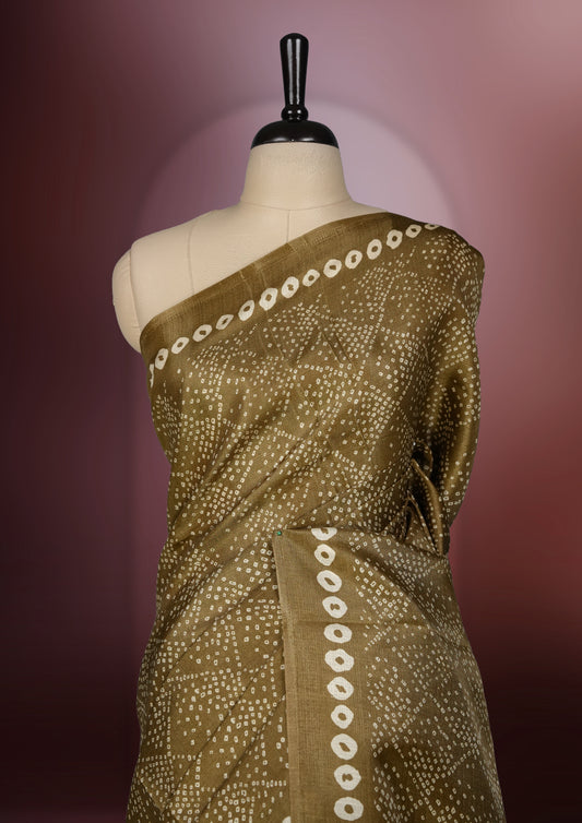 Golden brown colour saree with dotted tie dye patterns and cream circular border motifs & The pallu features exquisite Madhubani inspired designs in earthy hues,Paired with matching blouse, ideal for festive wear.