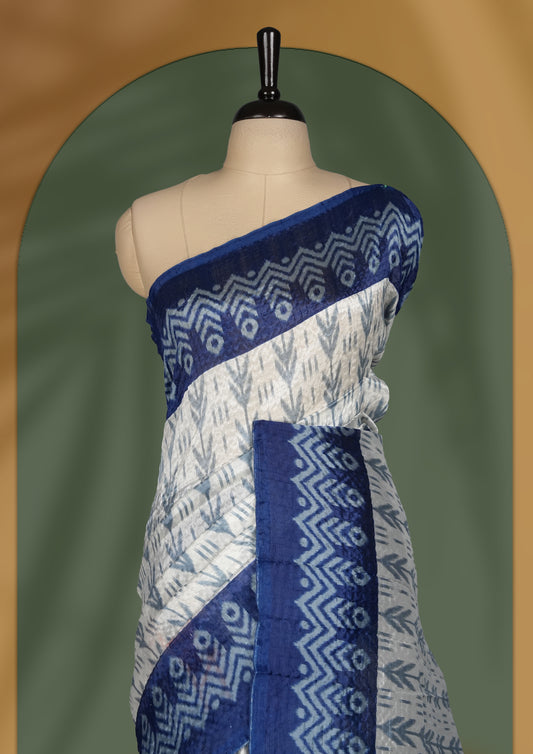 Classic off white colour saree adorned with intricate blue tribal motifs and rich woven patterns on the pallu and border & Paired with matching blouse.