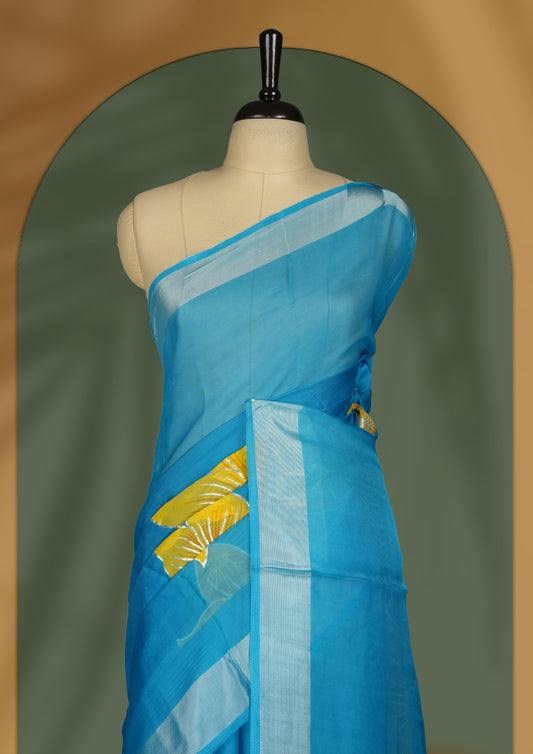 Sky blue colour saree with vibrant yellow floral prints and a soft striped border & Includes matching blouse piece.