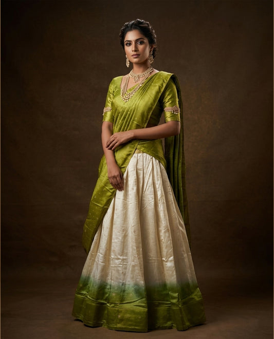 Off white colour semi stitched half saree featuring elegant zari buttas on the body, paired with a contrast pastel green border and matching striped dupatta,paired with matching blouse piece.