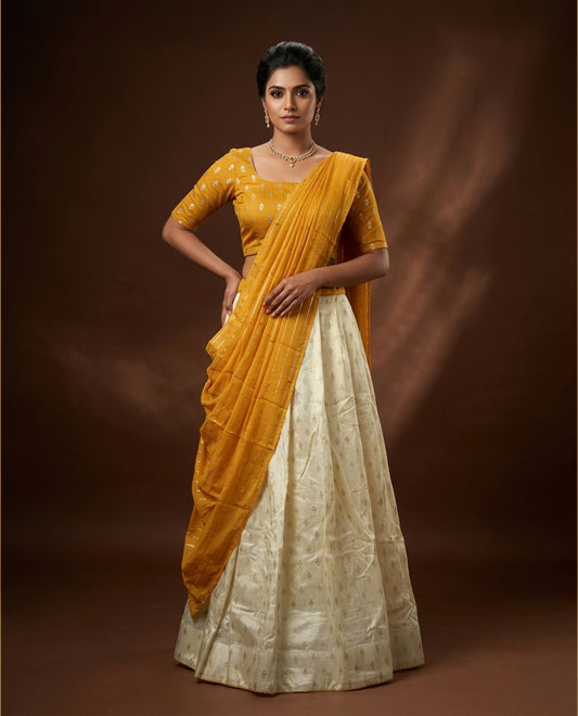 Off white colour semi stitched half saree featuring elegant zari buttas on the body, and contrast mustard colour with striped dupatta,paired with matching blouse piece.