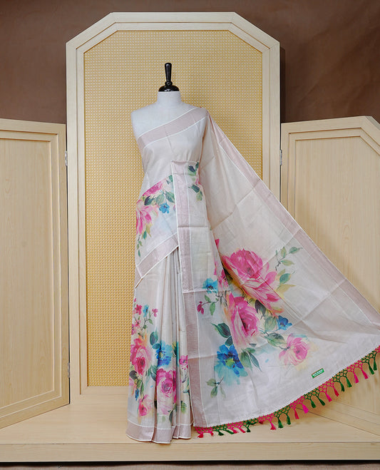 Cream Colour Tissue Kerala Saree Featuring Digital Floral Prints Across The Body, Enhanced With A Rose Gold Zari Border, Finished With Pink & Green Tassels And A Matching Blouse Piece