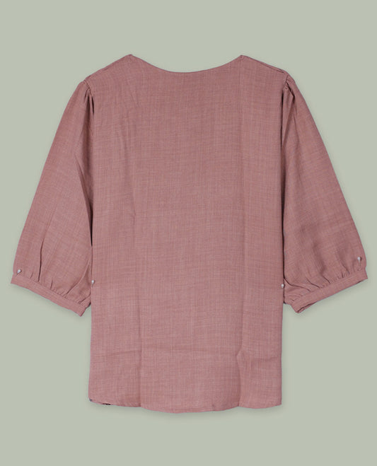 Dusty rose round-neck top with three-quarter sleeves and placement floral print in muted blue, green, and burgundy tones along the front hem and side.