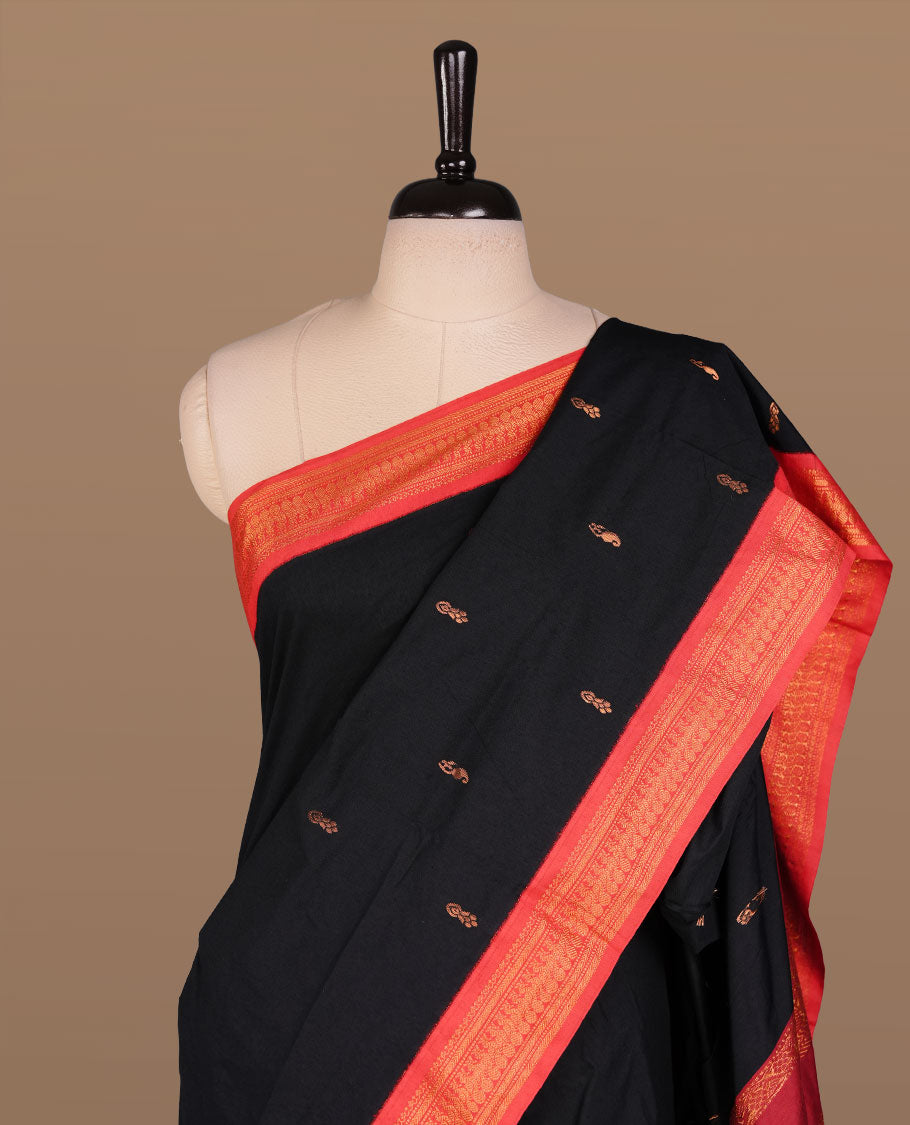 Black colour kalyani cotton saree featuring antique zari motifs on body, complemented by red colour with Antique zari border, paired with matching blouse piece.