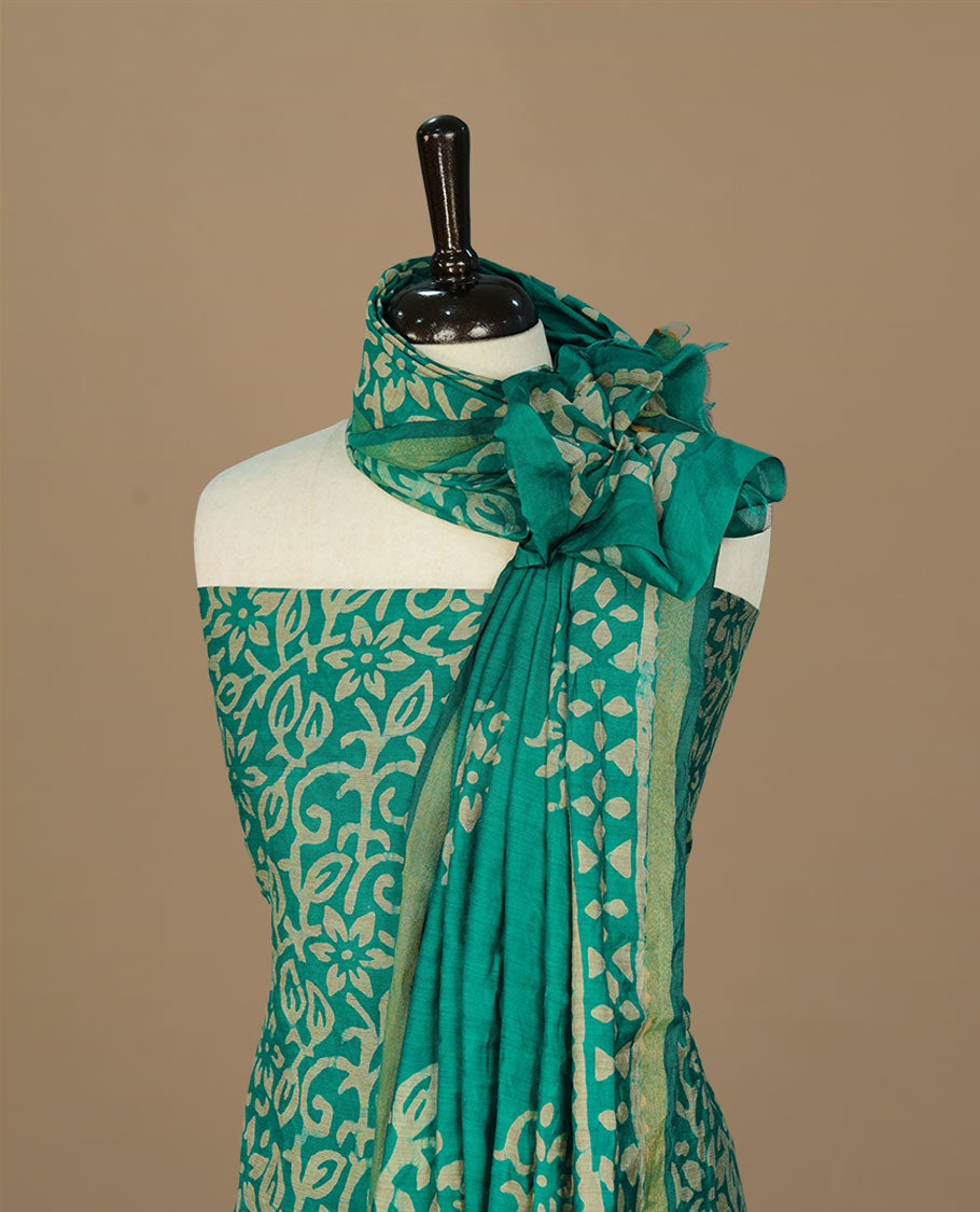 Green colour salwar suit matieral featuring cream colour floral kodi printed on body, paired with matching bottom and dupatta.