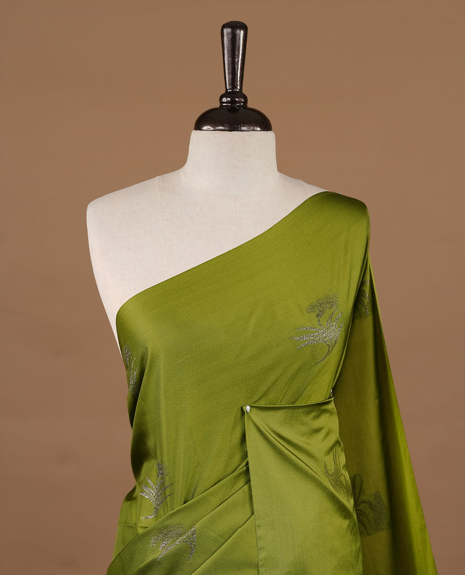 Olive soft silk saree features a sleek borderless design with intricate antique zari motifs, flowing into a seamless self colored pallu and a matching blouse piece.