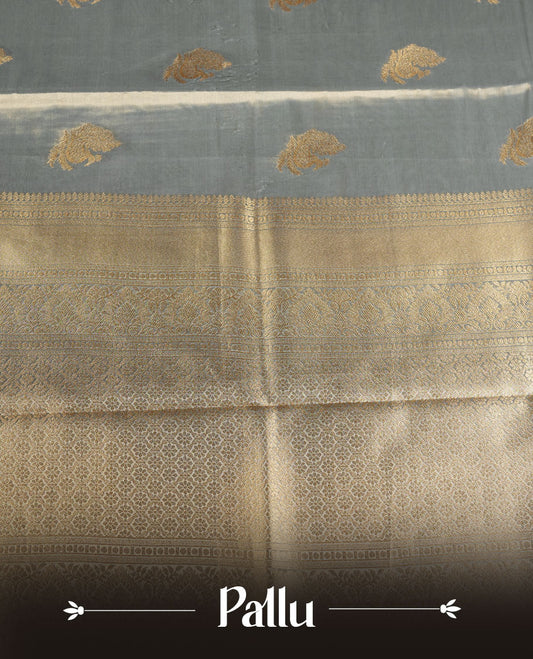 Dual tone light blue and gold colour tissue brocade saree featuring antique gold zari motifs on the body with a rich traditional zari border and pallu, paired with a matching blouse piece.