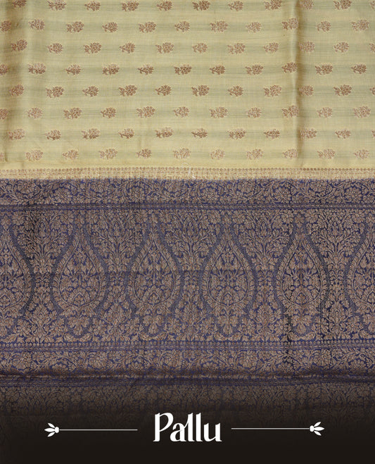 Cream colour Banaras tussar silk saree featuring elegant gold zari buttas across the body, complemented by a contrast Navy Blue border with rich zari detailing. Comes paired with a matching blouse piece.