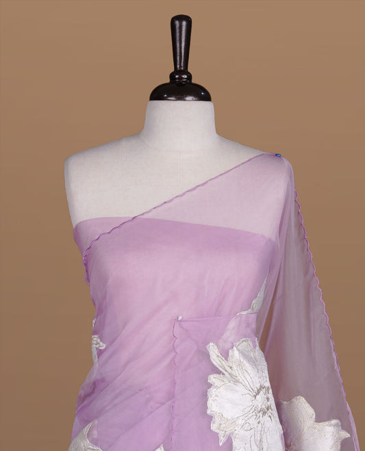 Lavender colour semi organza saree featuring white floral & gold thread pattern, highlighting scalp design border, paired with matching blouse piece.