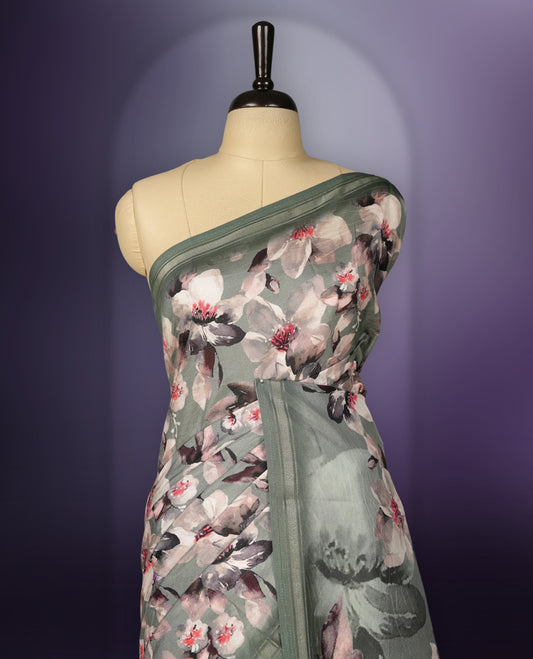 Pastel green saree adorned with elegant floral prints on the body, enhanced with a subtle matching border, complemented by a beautifully printed pallu featuring blooming flowers, and paired with a matching blouse.