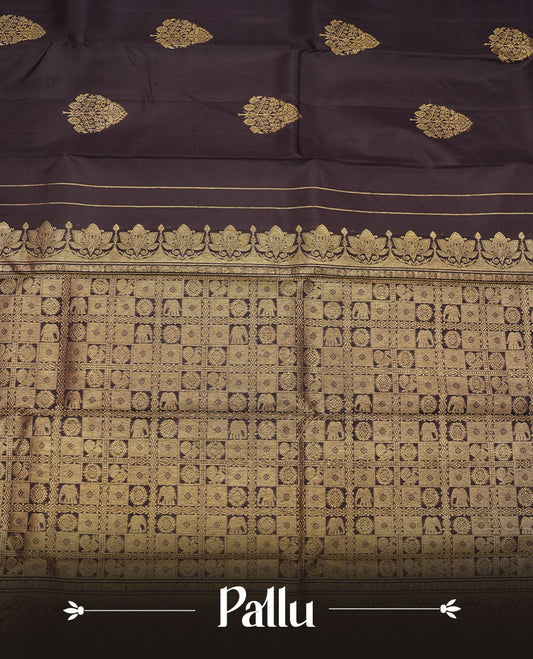 Deep coffee brown colour pure traditional Kancheepuram silk saree adorned with elegant zari tree motifs across the body, complemented by a rich zari woven border with a subtle green edge, paired with a matching blouse piece.