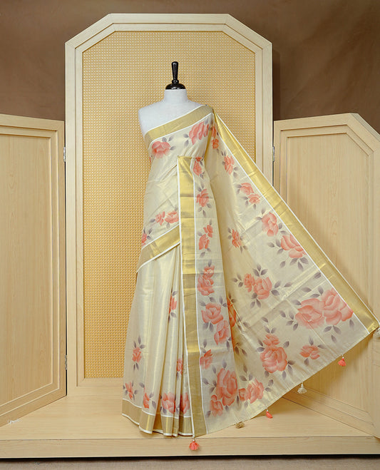 Cream Colour Tissue Kerala Saree Featuring Digital Peach Rose Prints Across The Body, Enhanced With A Gold Zari Border , Finished With Peach & White Tassels And A Matching Blouse Piece