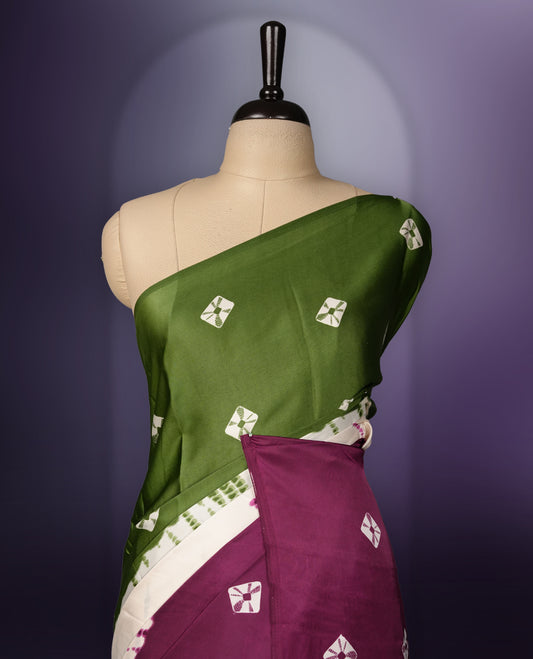 Rich green and purple saree adorned with small woven motifs on the body, enhanced by a contrast border, complemented with a traditional patterned pallu, and paired with a matching blouse.