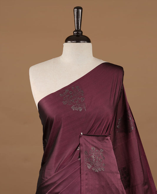 Burgundy soft silk saree features a sleek borderless design with intricate antique zari motifs, flowing into a seamless self colored pallu and a matching blouse piece.