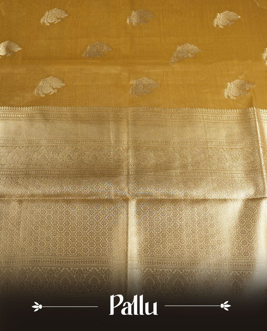 Gold colour tissue brocade saree featuring all-over zari floral motifs on the body, a rich traditional zari border and an intricately woven pallu, paired with a matching blouse piece.