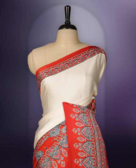 Cream colour saree enhanced with a vibrant red border and pallu, adorned with intricate blue and grey traditional motifs, comes with a matching blouse.
