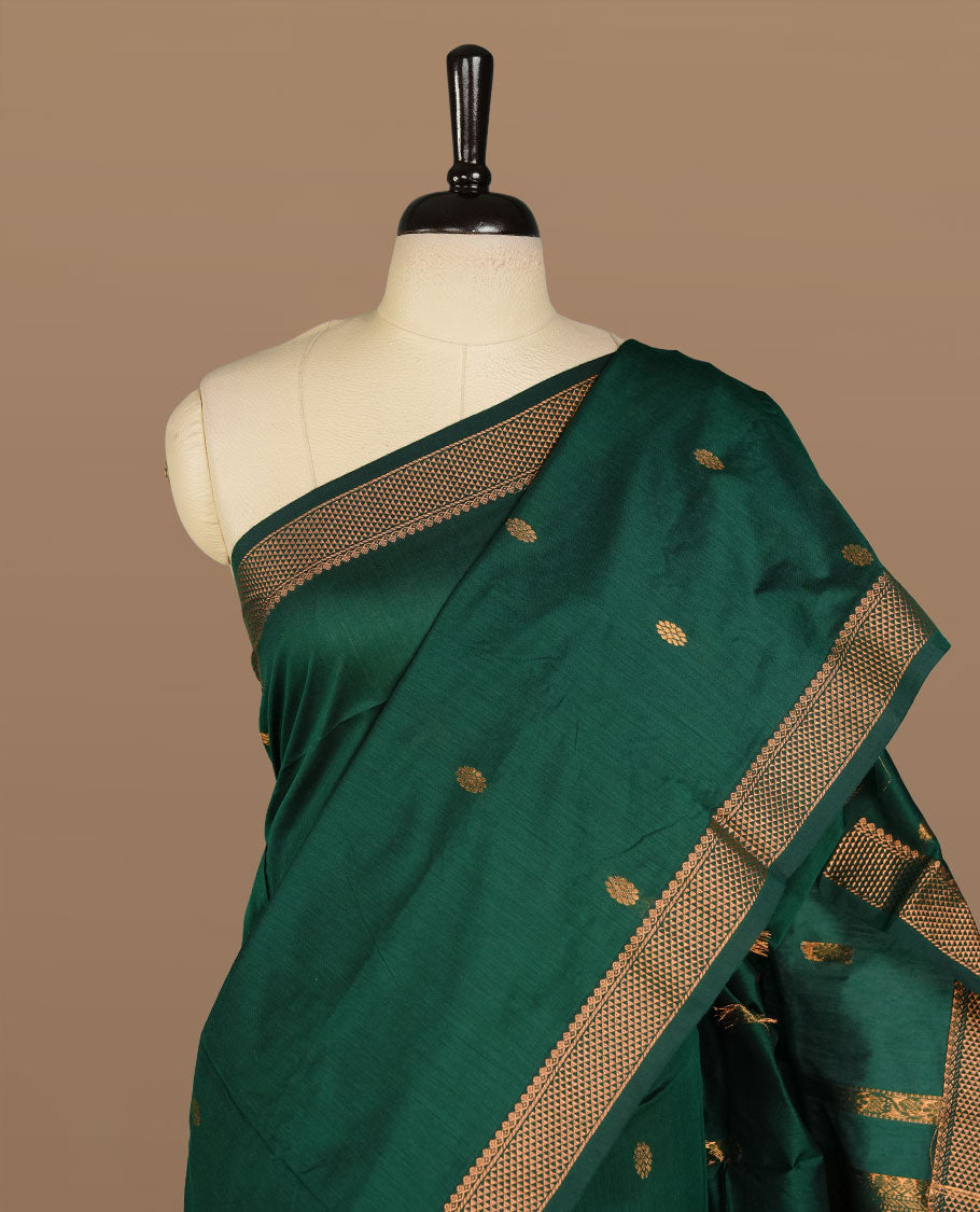 Dark green colour kalyani cotton saree featuring gold zari motifs on body, complemented by selfcolour with Antique zari border, paired with matching blouse piece.