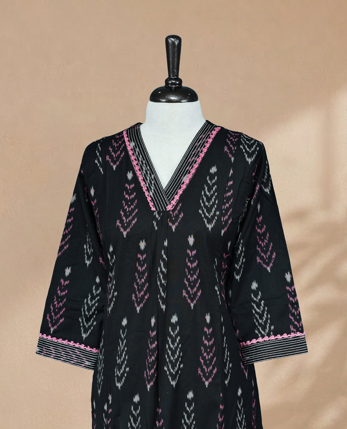 Black Kurti featuring pink and cream prints across the body, a V-shaped neckline with thread detailing, and 3/4 sleeves with a matching design.