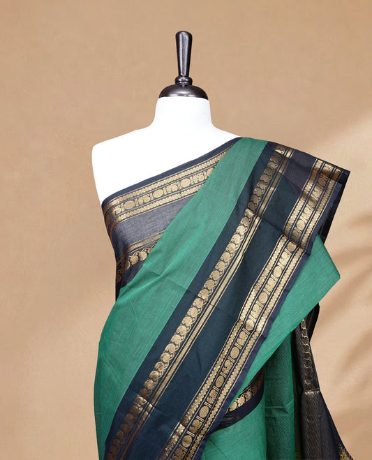 Green colour chettinad saree featuring Elegant Plain on body, complemented by contrast black colour with Gold zari border, paired wih matching blouse piece.