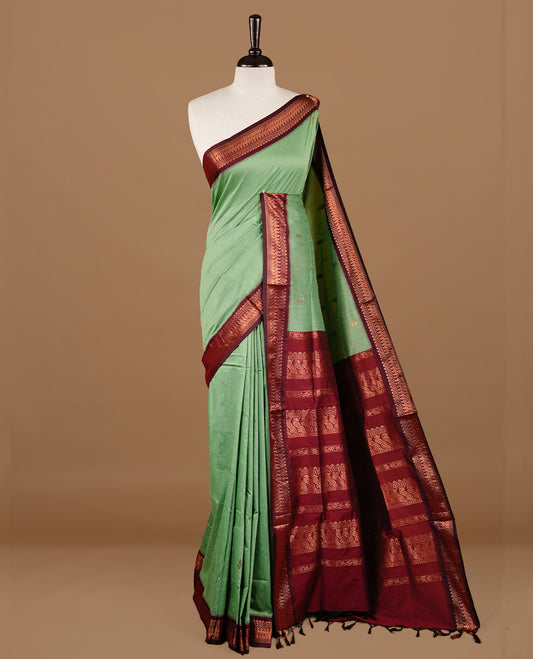 Pista green colour kalyani cotton saree featuring gold zari motifs on body, highlighting contrast Maroon colour with Antique gold zari border, paired with matching blouse piece.
